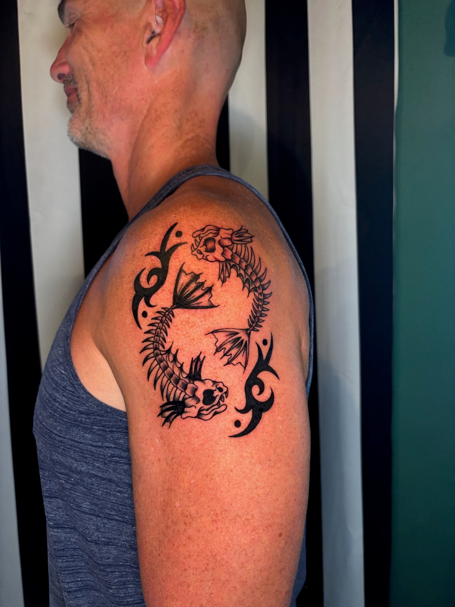 Tribal dragon shoulder tattoo with skull and floral elements, bold black