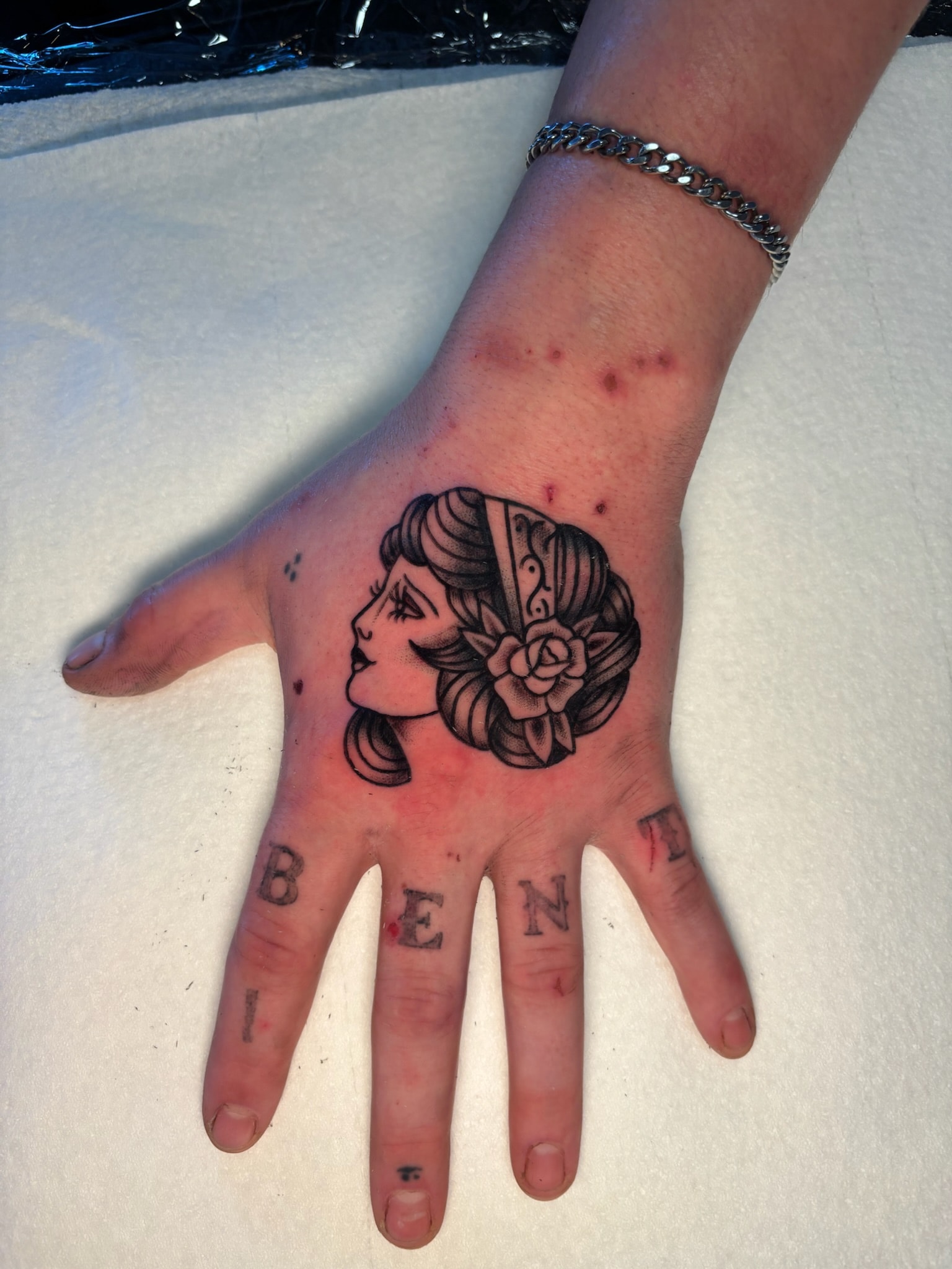 Hand tattoo of woman profile with rose flower, neo-traditional