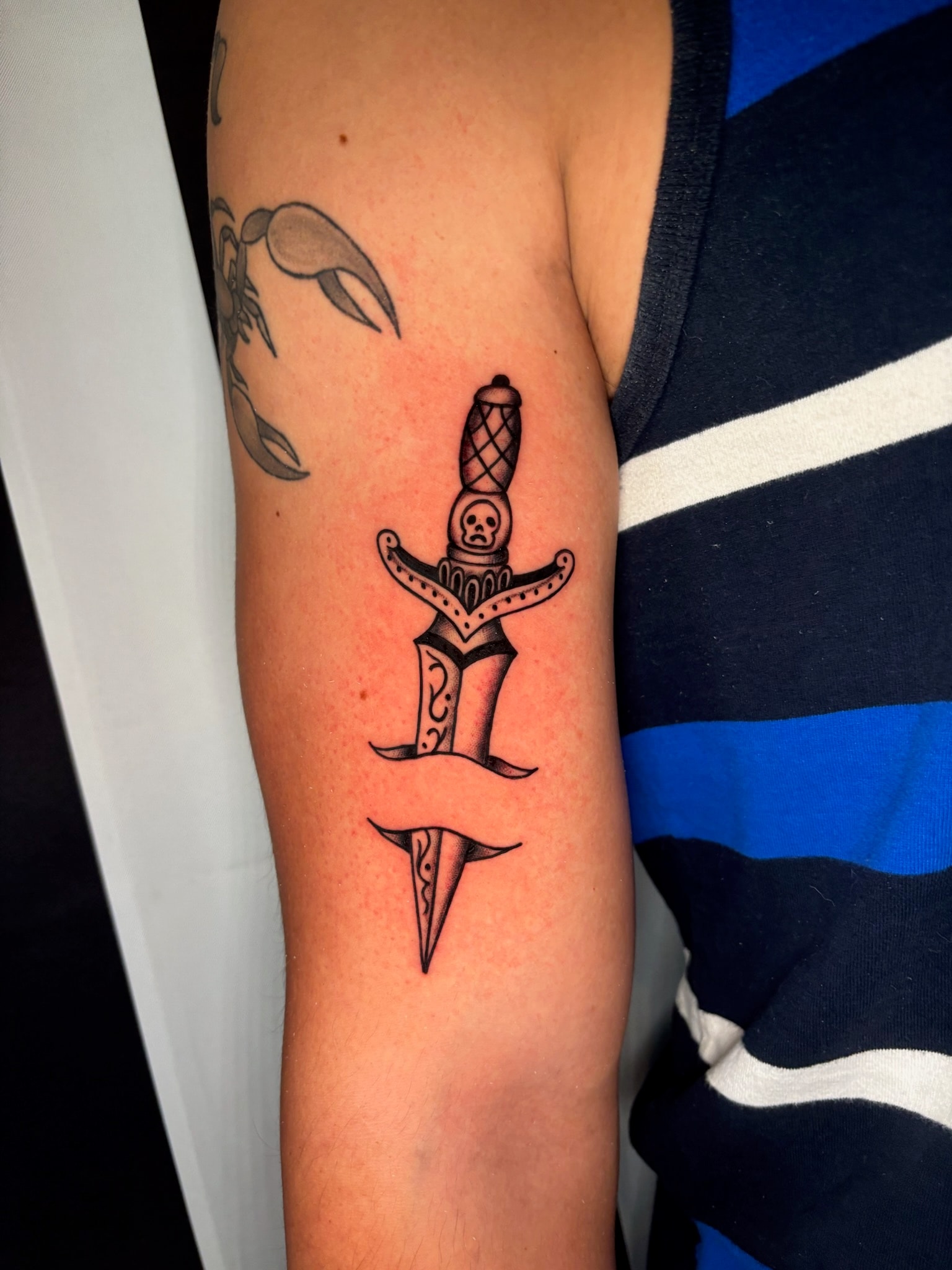 Decorative dagger tattoo on arm, black and grey